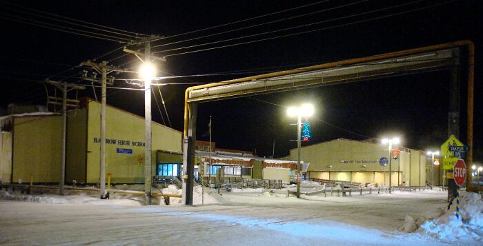 Snow-covered street at night near a high school, illustrating extreme weather conditions and powerful weather records.