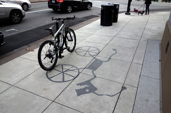 Bicycle casting clever shadow art installation on sidewalk, transforming ordinary objects into creative shadow art.
