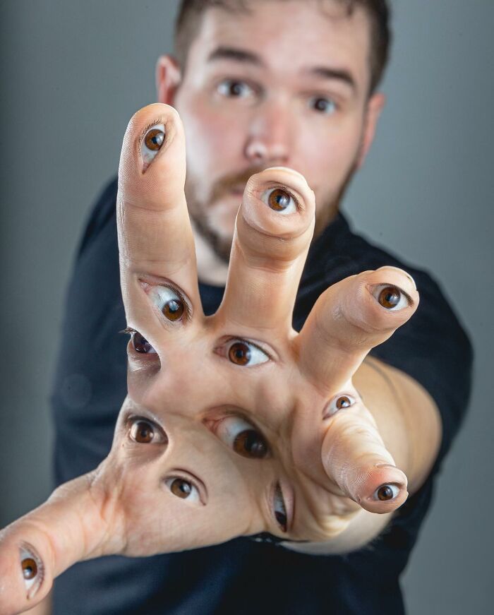 Man with a hand covered in multiple realistic eyes, showcasing amazing logic-challenging photo manipulations artwork.