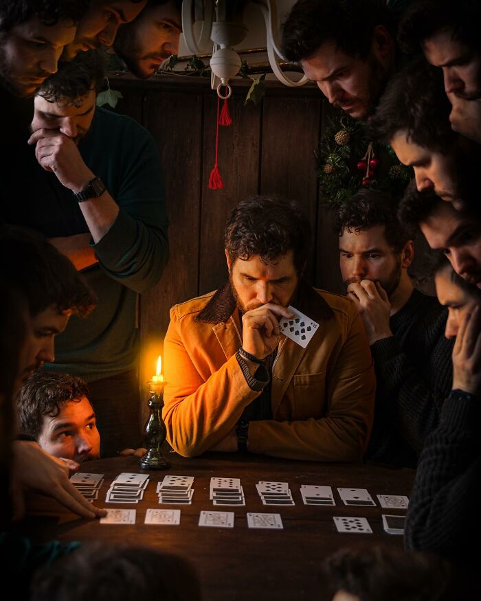 Man in orange jacket surrounded by multiple versions of himself, creating a logic-challenging photo manipulation with playing cards.