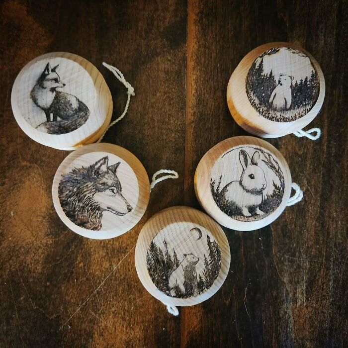 Wood-burned artworks by Canadian artist Kat Slota featuring detailed animal designs on circular wooden pieces.