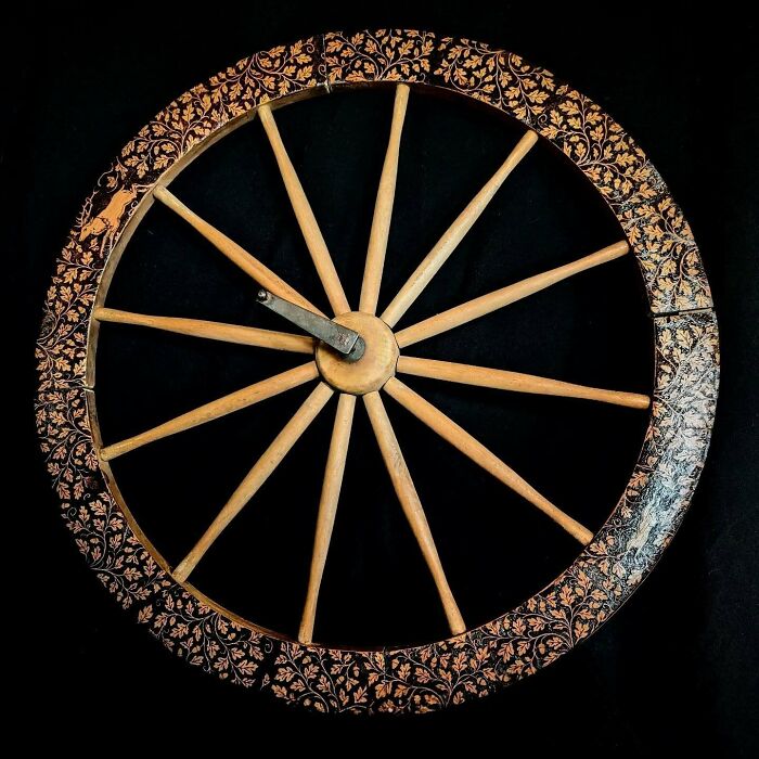 Wood-burned wooden wheel artwork by Canadian artist Kat Slota, featuring intricate fire-created floral patterns on the rim.