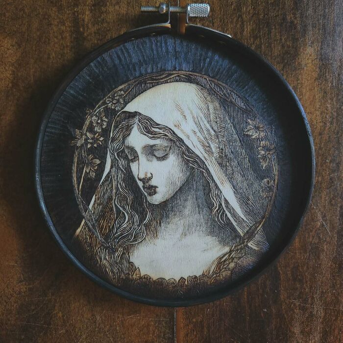 Wood-burned artwork by Canadian artist Kat Slota featuring a detailed portrait of a woman with long hair and floral accents.