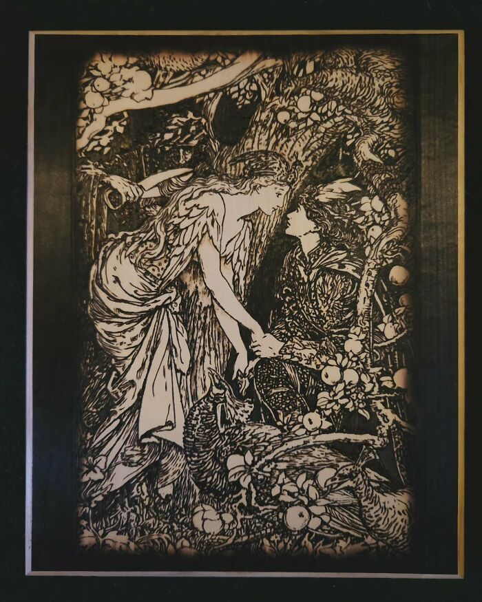 Wood-burned artwork by Canadian artist Kat Slota featuring two figures in a detailed forest scene created using fire.