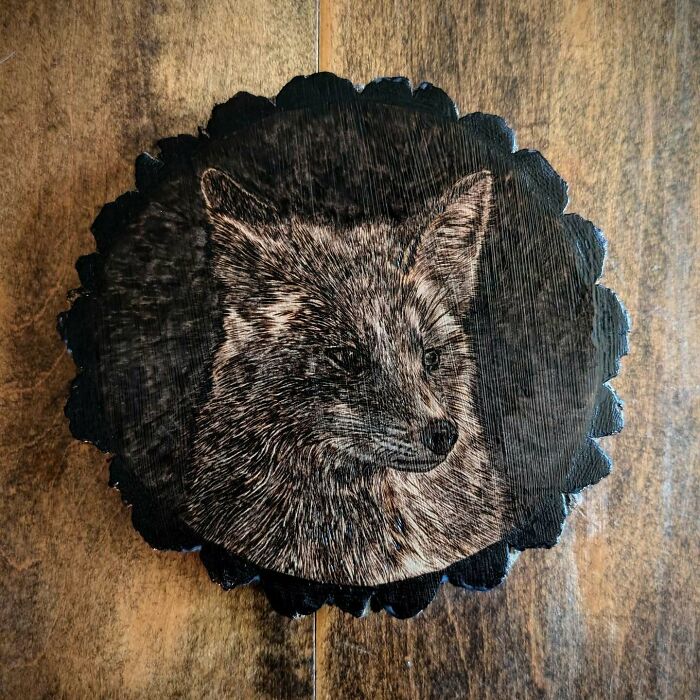 Wood-burned artwork of a detailed fox portrait on a natural wood slice by Canadian artist Kat Slota using fire techniques.