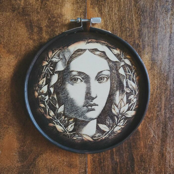 Wood-burned artwork by Canadian artist Kat Slota depicting a detailed female portrait surrounded by leaves in a circular frame.