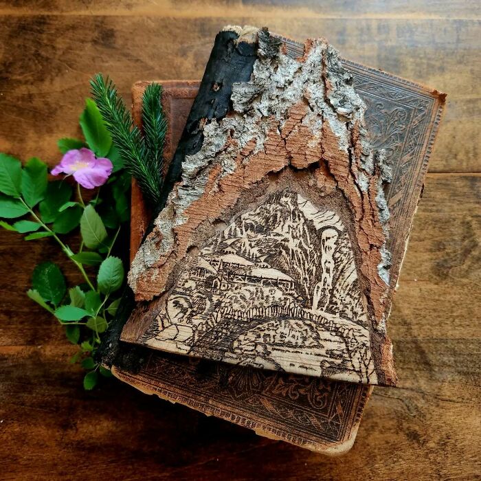 Wood-burned artwork by Canadian artist Kat Slota on bark, depicting a mountain village scene with natural textures.