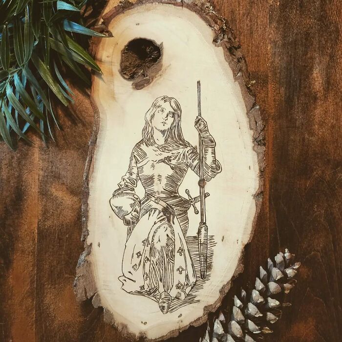 Wood-burned artwork on wood slice depicting a medieval woman with spear, created by Canadian artist Kat Slota using fire.