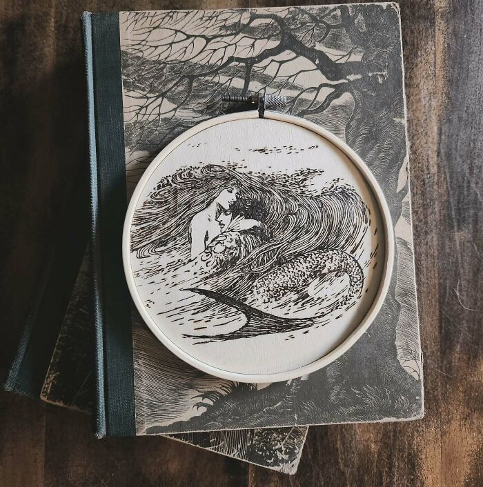 Wood-burned artwork of a mermaid created by Canadian artist Kat Slota using fire on a wooden embroidery hoop.