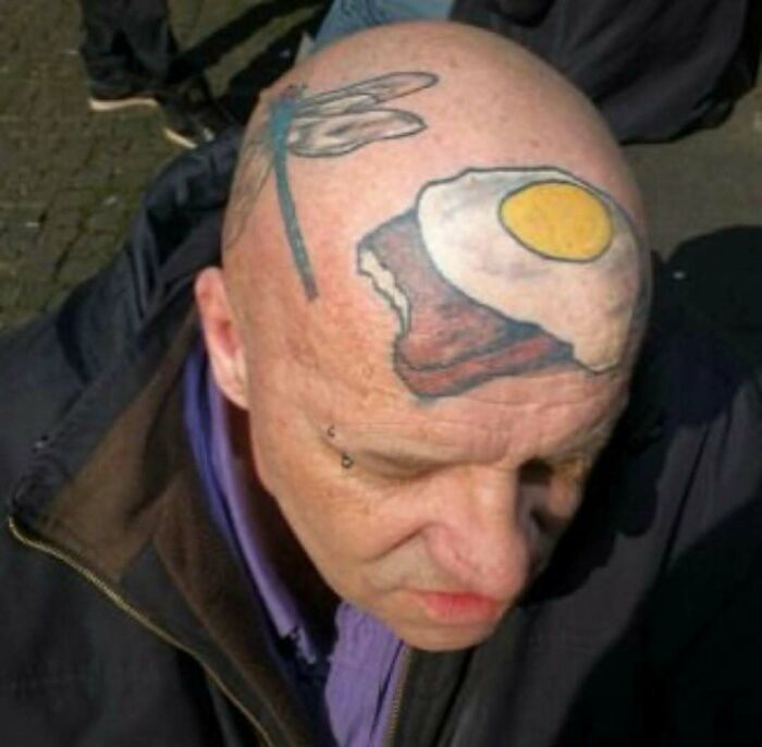 Bald man with an unusual tattoo of a fried egg and toast on his head, showcasing one of the awful tattoos.