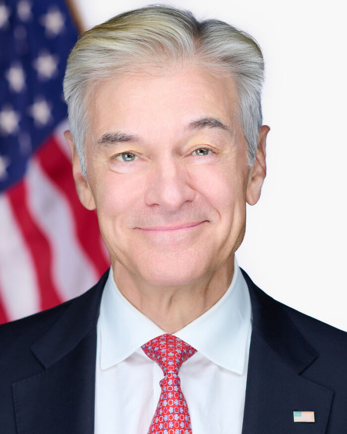Older man in a suit and red tie smiling with an American flag in the background, related to celebs people can't stand.