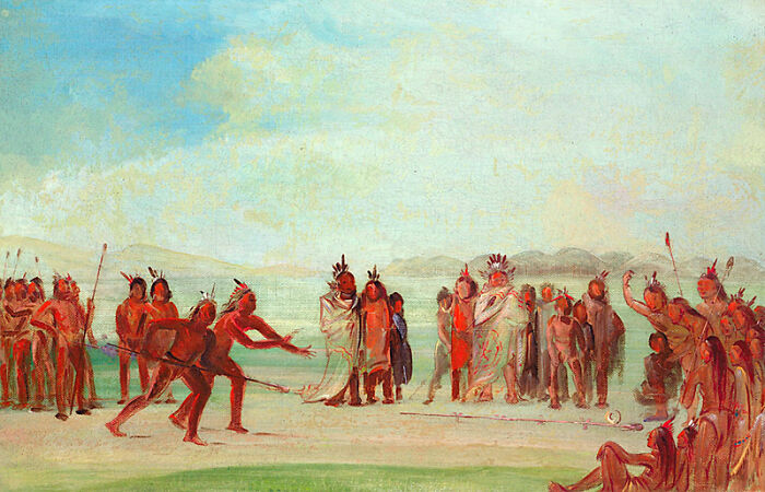 Native Americans playing an intense, dangerous historical sport outdoors, surrounded by a large crowd of spectators.