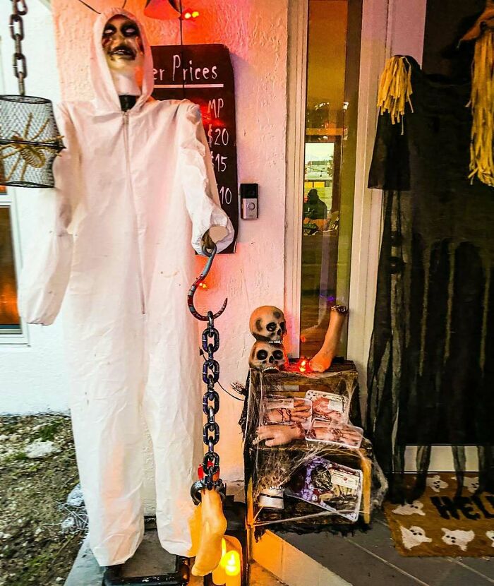 Outdoor Halloween decorations with spooky skeletons, severed limbs, and eerie props creating a creepy festive display.