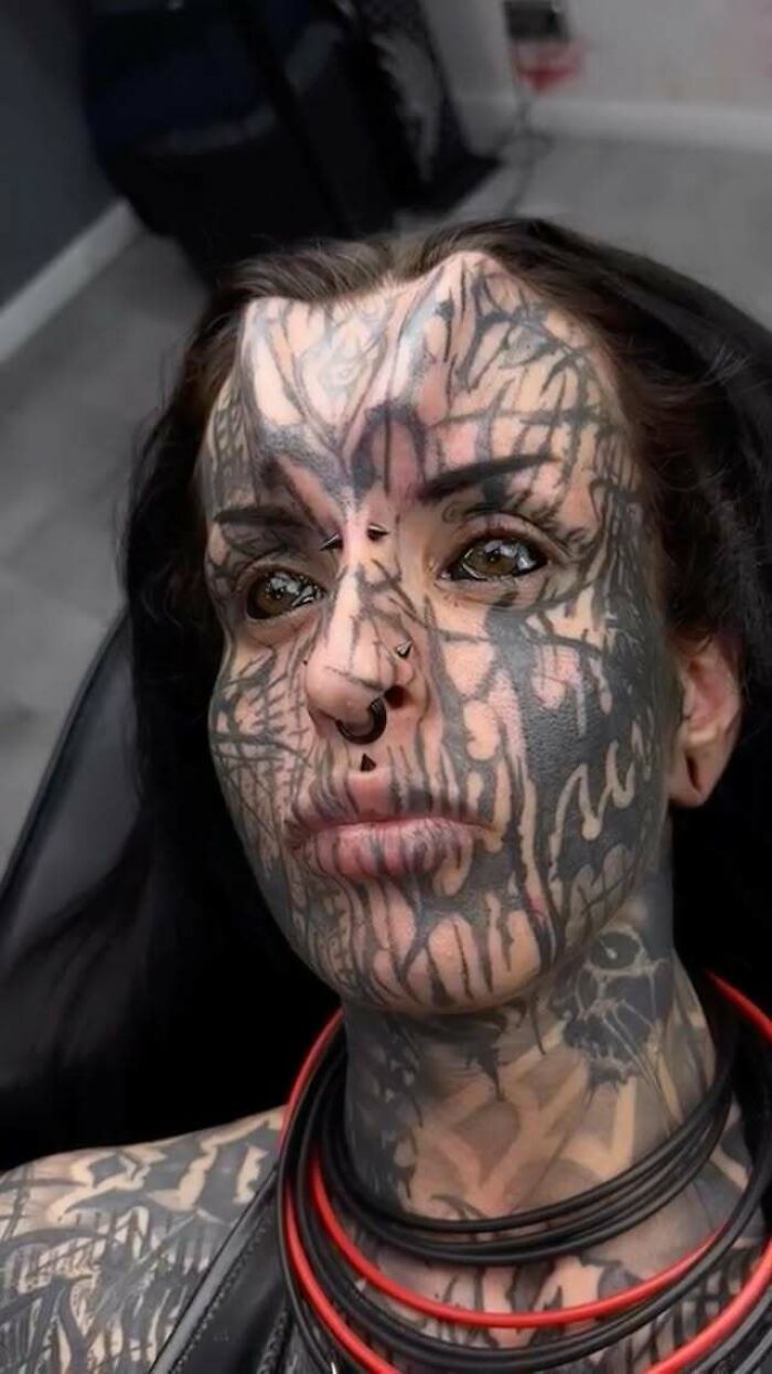 Tattooed woman with facial tattoos and nose piercings, showing the area where her nose was cut off and preserved.