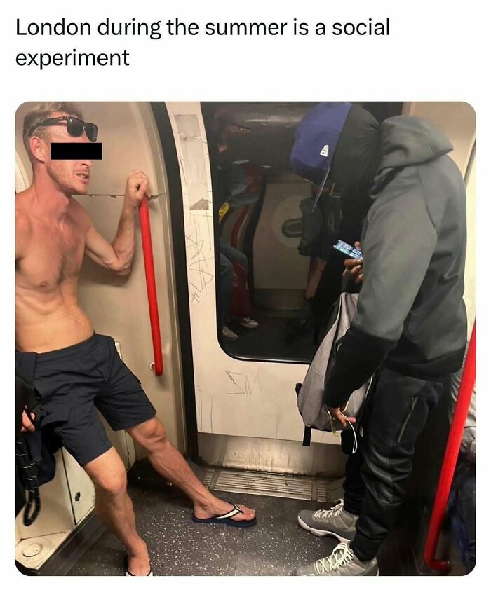 Man wearing shorts and flip-flops leaning inside a London Underground train during summer, showing unapologetically British behavior.