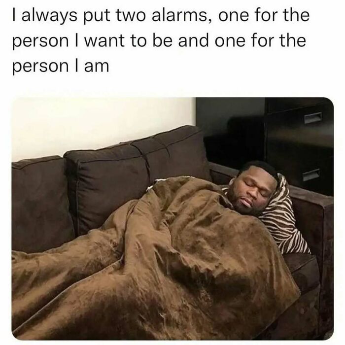 Man wrapped in blanket sleeping on couch with relatable work meme about setting two alarms for different selves.