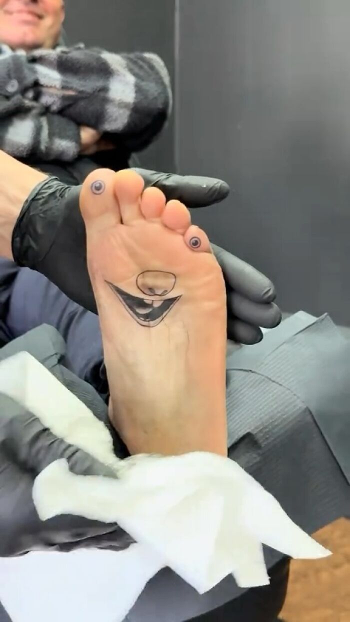 A foot tattoo of a smiling face with eyes on toes, one of the 75 awful tattoos showing poor decision making.