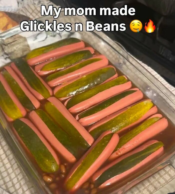 A glass dish filled with hot dogs and pickles in beans, an unusual meal that might need a priest or an exorcist.