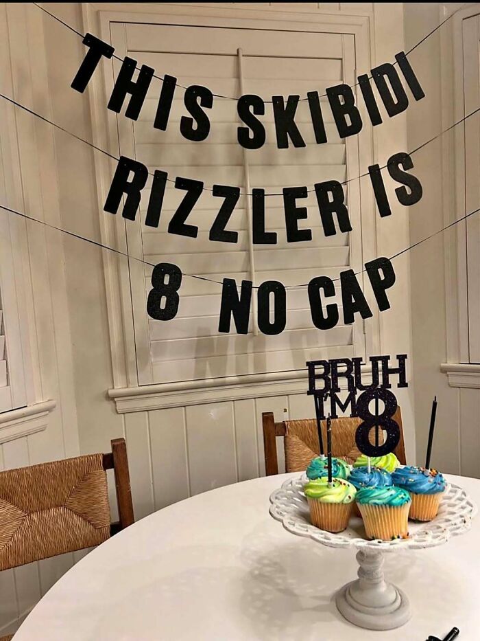 Cupcakes on a white stand with blue and green frosting and meme decorations under posts that hit different at 3AM banner.