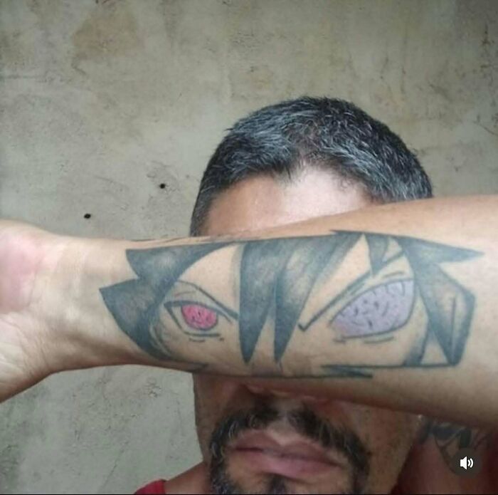 Man showing awful tattoo of anime eyes on forearm, illustrating people allergic to smart decisions in tattoo choices