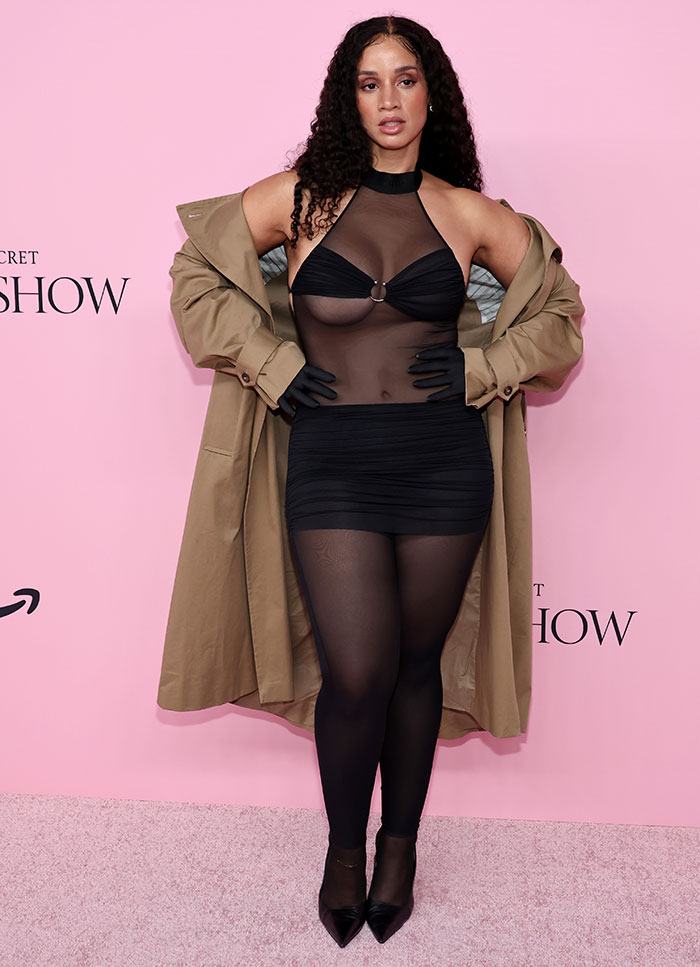 Model wearing sheer black dress and trench coat posing at Victoria's Secret Fashion Show 2025 worst dressed with risqué looks.