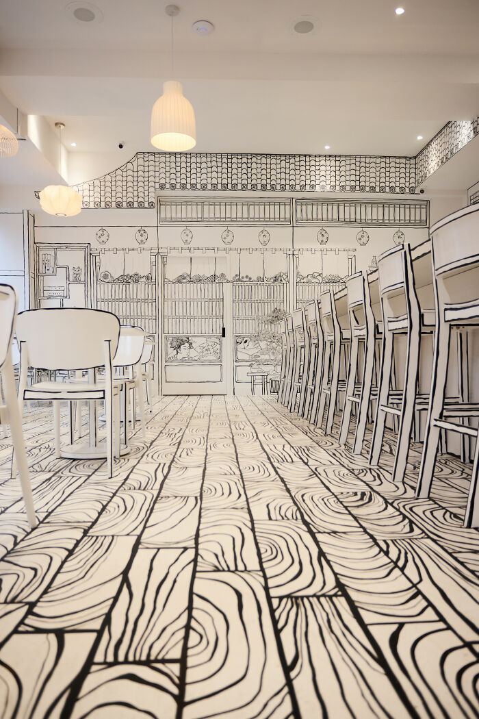 Interior of a 2D restaurant in NYC with black and white drawings creating a flat, illustrated dining space effect. Interior of a 2D restaurant in NYC with black and white drawings creating a flat, illustrated dining space effect.