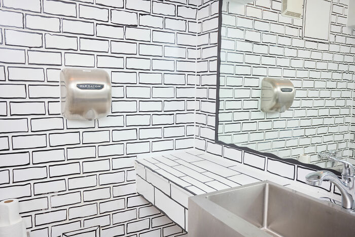 Bathroom in a 2D restaurant in NYC with black and white drawn brick walls and a hand dryer above the sink. Bathroom in a 2D restaurant in NYC with black and white drawn brick walls and a hand dryer above the sink.