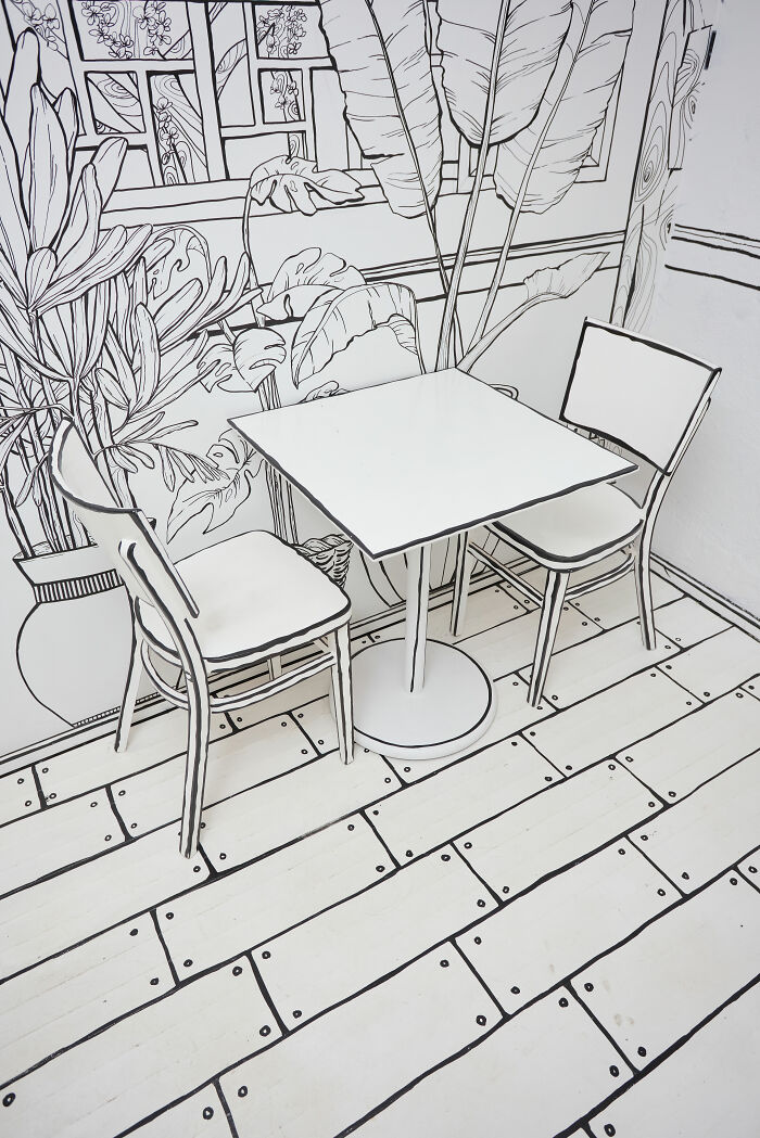 Interior of a 2D restaurant in NYC with black and white line art furniture and plant drawings creating a cartoon-like feel. Interior of a 2D restaurant in NYC with black and white line art furniture and plant drawings creating a cartoon-like feel.