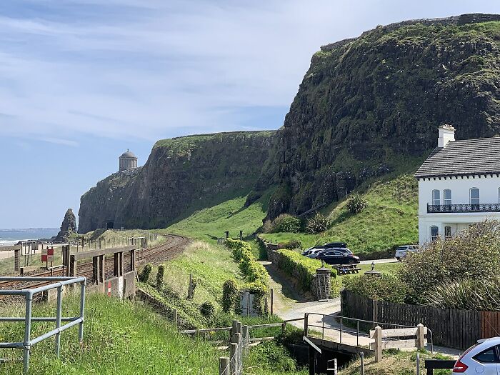 Coastal landscape with cliffs, a small railway track, and countryside homes showcasing unbelievable country facts.