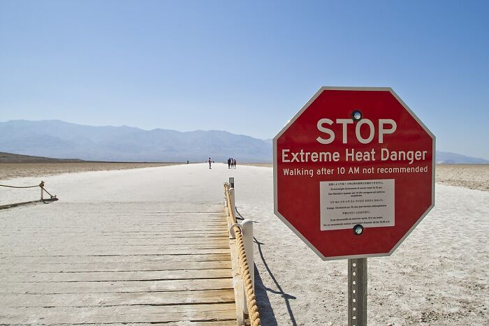 Stop sign warning of extreme heat danger on a desert boardwalk illustrating incredible weather records on our planet