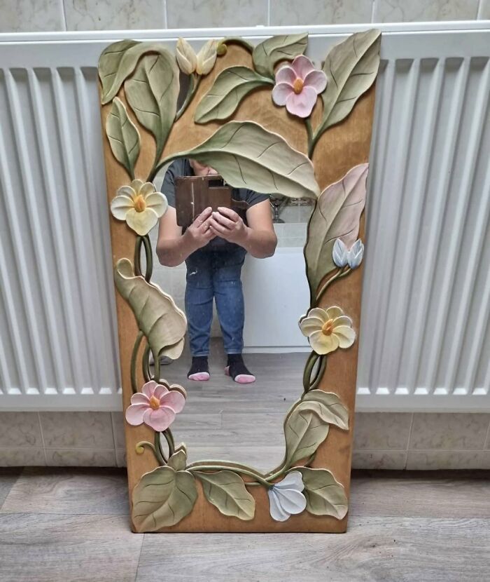 Mirror with floral frame reflecting person holding tablet, showcasing hilarious times people tried to sell a mirror reflection.