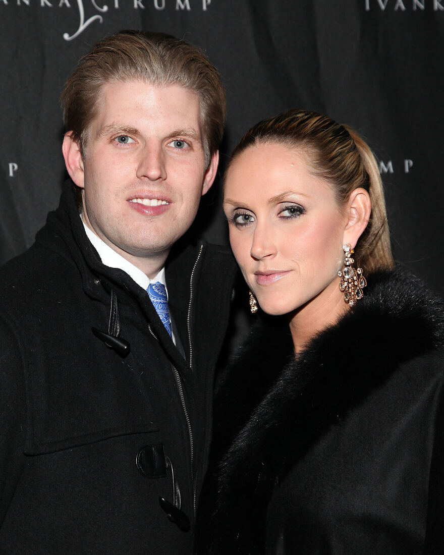 Eric Trump and Lara Trump posing together at an event wearing formal black coats with elegant accessories.