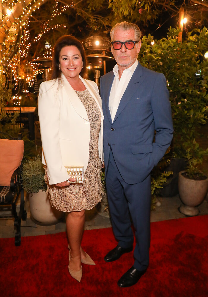 Pierce Brosnan's wife at event, wearing a white blazer and patterned dress, showing off slimmer frame at 62 years old. Pierce Brosnan's wife at event, wearing a white blazer and patterned dress, showing off slimmer frame at 62 years old.