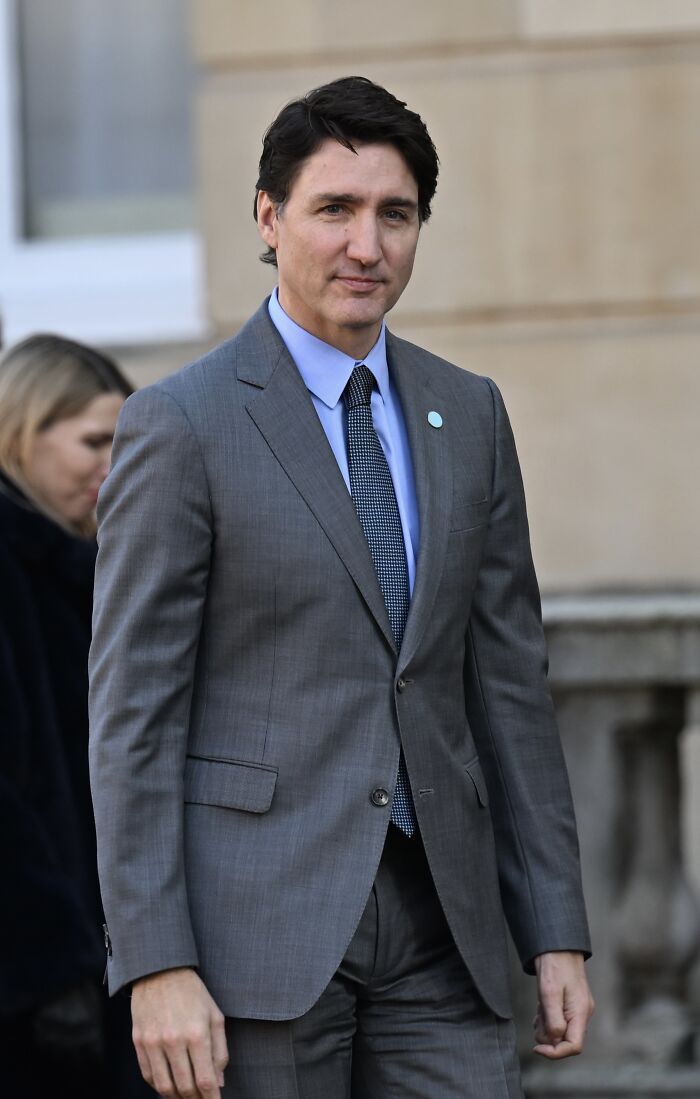 Justin Trudeau in a grey suit outdoors, linked to Katy Perry romance rumors after ex-wife's cryptic message.