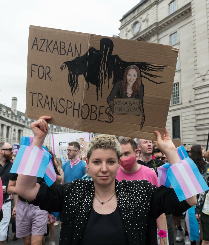 Protester holding sign referencing Keira Knightley amid trans activists' boycott of Harry Potter event.