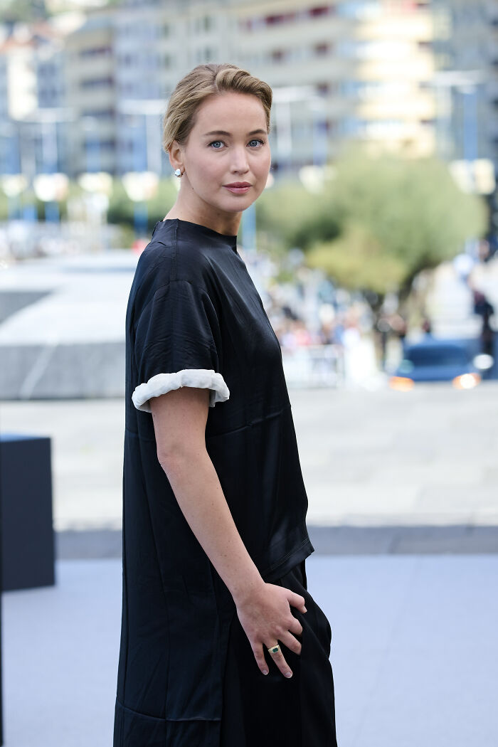 Jennifer Lawrence at Paris Fashion Week wearing black dress, sparking frenzy over plastic surgeon arrests in LA discussion.