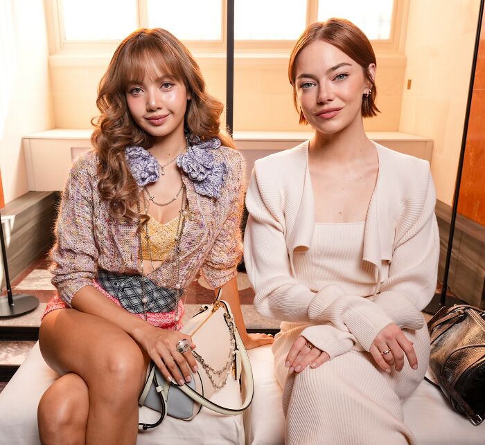 Emma Stone sitting in a Louis Vuitton outfit with another woman, sparking plastic surgery speculation in photoshoot.