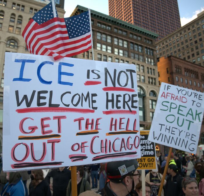 Protesters in a city holding signs against ICE amid public backlash over Kylie Jenner fake arrest video controversy.