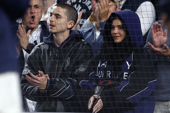 Kylie Jenner and Timoth&eacute;e Chalamet attending a sports event together, captured in a candid moment behind a net.