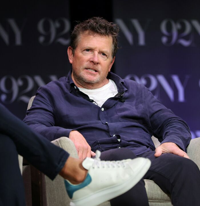 Michael J. Fox seated during an interview, sharing a heartbreaking update on his health in a casual setting.