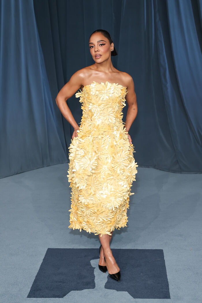 Woman in a yellow floral strapless dress posing at the 2025 Academy Museum Gala red carpet event.