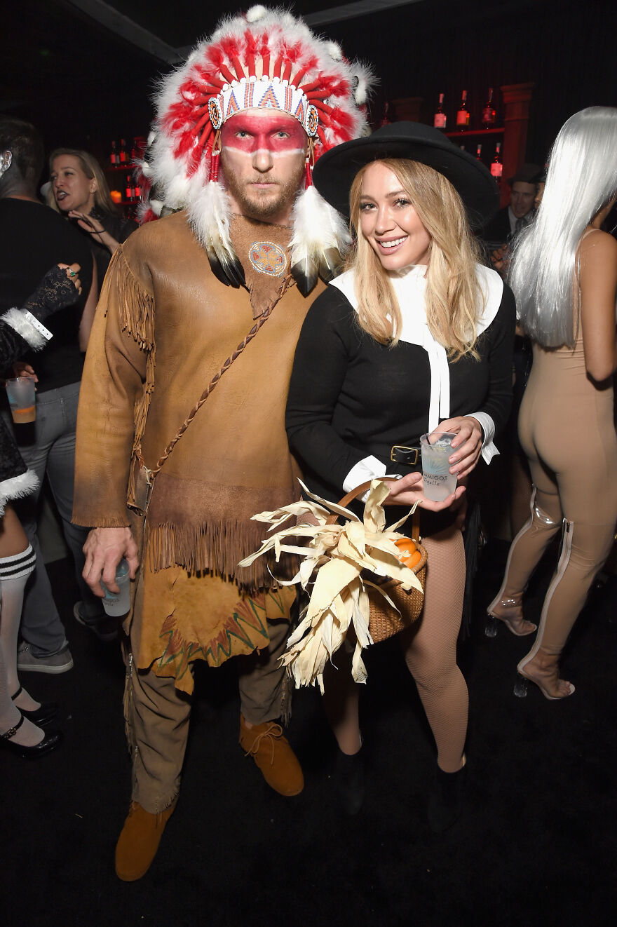 Celebrity couple posing in unconventional Halloween costumes at a party, highlighting lack of common sense in costume choices.