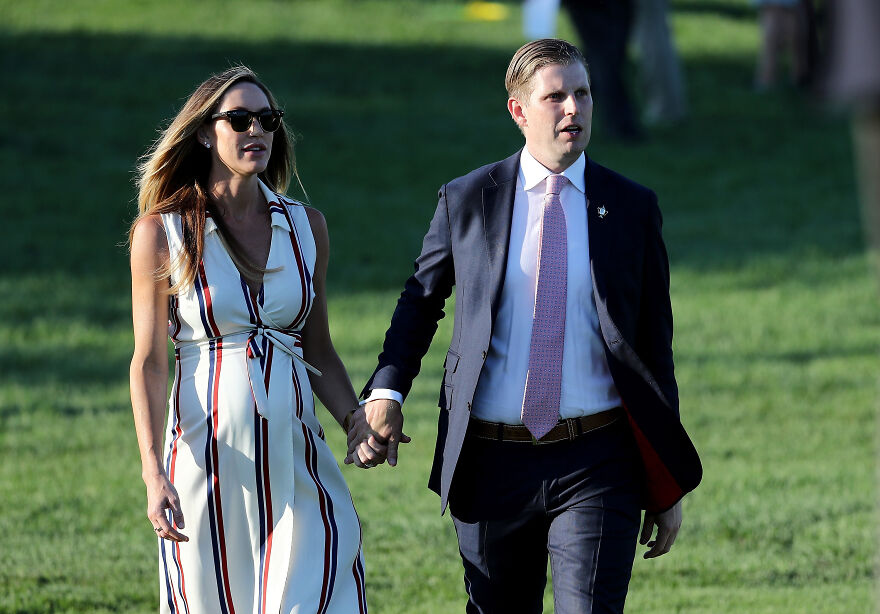 Lara Trump holding hands with a Eric Trump outdoors, wearing a white dress with stripes, showcasing early years to MAGA star look.