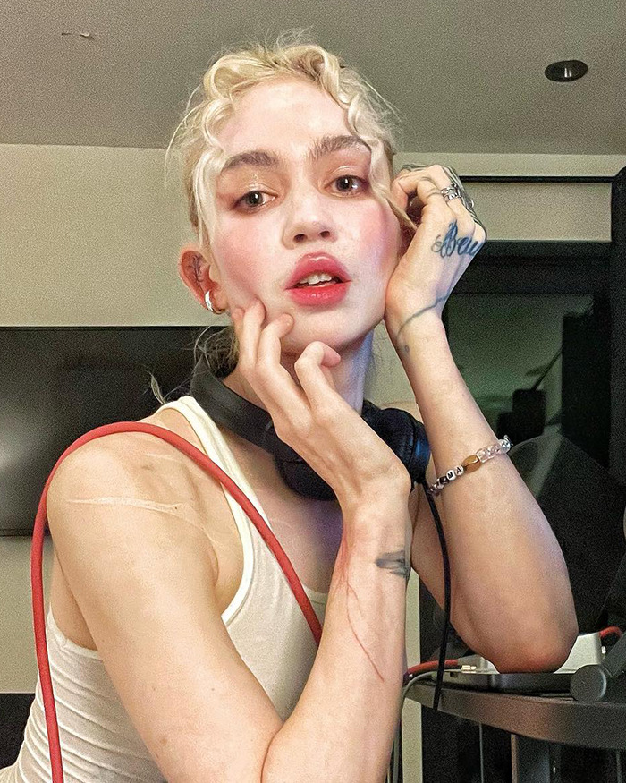 Persona rubia con camiseta blanca y audífonos, mostrando expresiones faciales en tendencia de celebridades que perdieron fanbases.