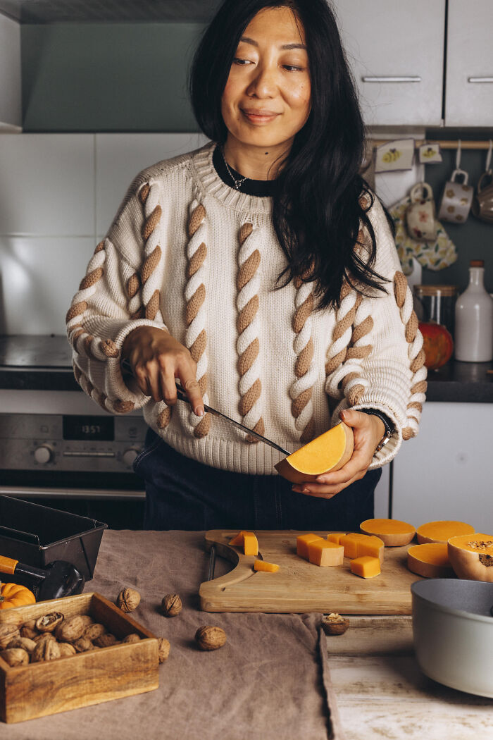 Woman preparing butternut squash in kitchen, cozy autumn setting for making butternut squash cake recipe.