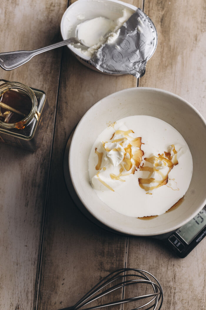 Bowl with creamy ingredients and honey, cream cheese, and whisk ready for cozy butternut squash autumn cake recipe preparation.