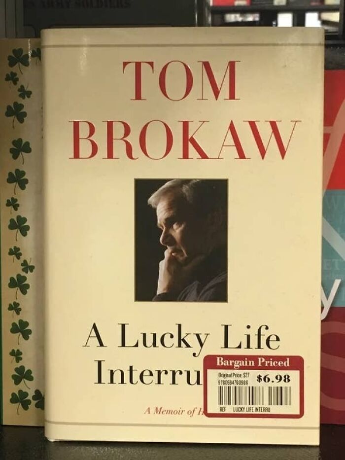 Book titled A Lucky Life Interrupted by Tom Brokaw with a bargain price tag, shown in an accidental comedy moment.