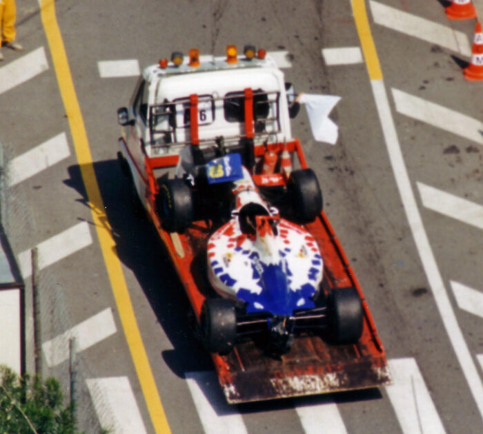 Race car being towed on a flatbed truck symbolizing funny events from history that capture unexpected moments and mishaps.