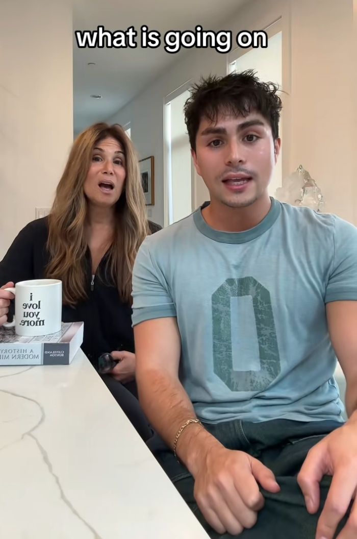 Man and woman reacting with surprise indoors, discussing man traveling to Europe to find grandmother's mysterious lockbox.