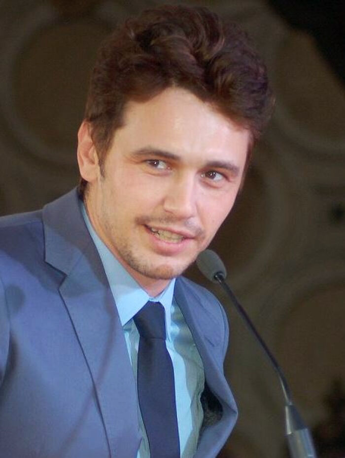 Young male celebrity in a suit speaking into a microphone, featured in celebs people can't stand discussions.